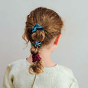 Copil purtând un set de 6 scrunchie-uri subțiri, multicolor, vedere din spate, pe fundal crem