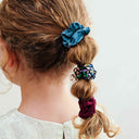 Copil purtând un set de 6 scrunchie-uri subțiri, multicolor, vedere din spate, pe fundal albastru