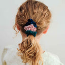 Copil purtând un set de 6 scrunchie-uri subțiri, multicolor, vedere din spate, pe fundal roz