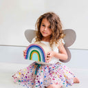 Copil ținând cutia Curcubeu Unicornland, purtând fustiță cu stele și aripi gri