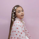 Copil purtând agrafele Cutey Kitten, fotografiat de aproape pe fundal roz