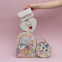 Geantă curcubeu Dreamwish, roz pastel alături de alte accesorii Mimi & Lula, pe fundal roz