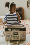 Copil lângă coșul Boom Box, purtând căști textile